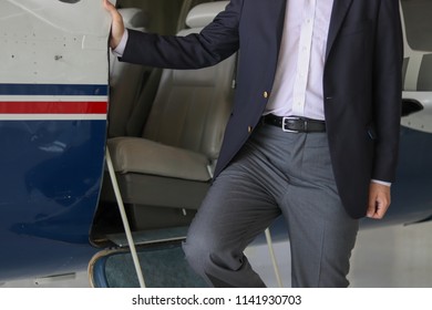 A Businessman That Is Stepping Off The Airplane, When He Is On A Business Trip For Work. He Is Traveling On A Plane.