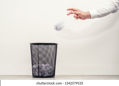 Businessman throwing waste paper to trash can in office