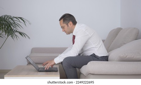 Businessman with tie sit on couch and look at computer, man work home, isolation