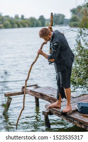 Businessman In Torn Suit Fishing On Desert Island