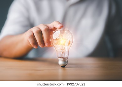 Businessman touching a bright light bulb. Concept of Ideas for presenting new ideas Great inspiration and innovation new beginning.