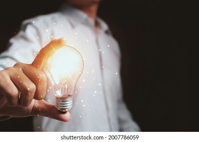 Businessman touching a bright light bulb. Concept of ideas for presenting new ideas Great inspiration and innovation new beginning. - Shutterstock ID 2007786059