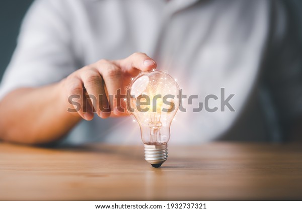 Businessman touching a bright light bulb.\
Concept of Ideas for presenting new ideas Great inspiration and\
innovation new\
beginning.