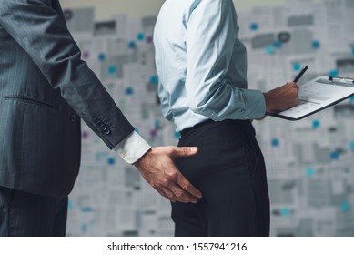 Businessman Touching His Female Colleagues Buttocks In The Workplace: Sexual Harassment And Discrimination Concept