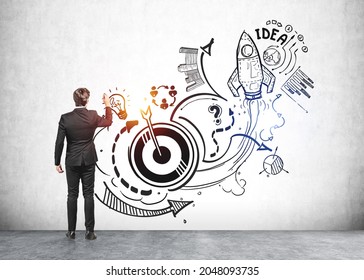 Businessman is touching sketch with icons of rocket launch, start up, light bulb, globe, bar and pie diagrams, teamwork, plan and arrow. Concept of inspiration and imagination for creative idea