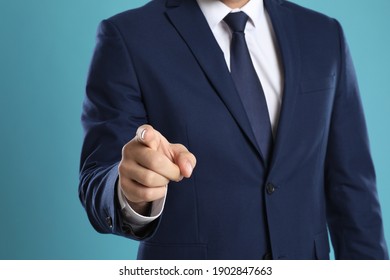 Businessman touching something on light blue background, closeup. Finger gesture