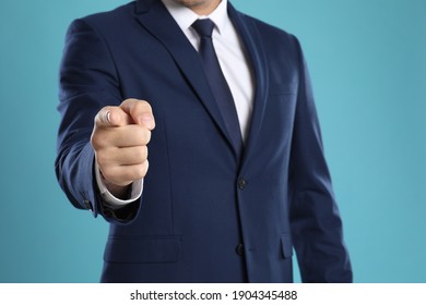 Businessman touching something on light blue background, closeup. Finger gesture