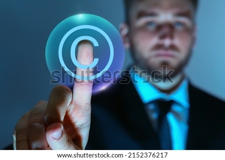 Businessman touching symbol of copyright on virtual screen against blue background, closeup