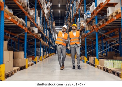 A businessman is touring his investor trough storage and pointing at goods and boxes on shelves. - Powered by Shutterstock