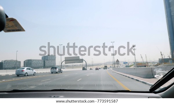 Businessman traveling by car\
in Dubai with a view of the car. View from the interior of the car\
on the streets of Dubai, the man behind the wheel of a car on a hot\
day