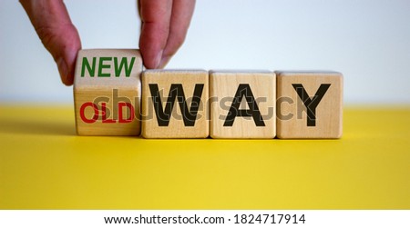 Businessman turns a cube and changes words 'old way' to 'new way'. Beautiful yellow table, white background. Copy space. Concept of new way choice.
