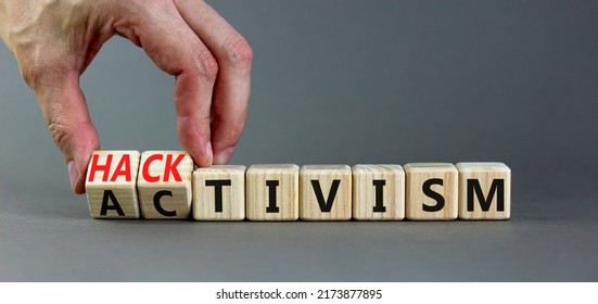 Businessman Turns Wooden Cubes And Changes The Word Activism To Hacktivism. Beautiful Grey Table Grey Background, Copy Space. 