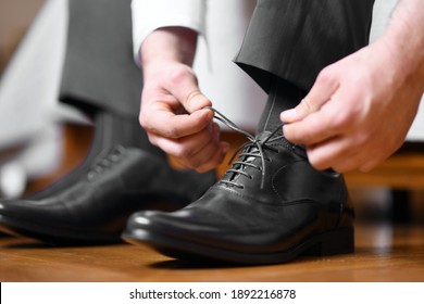 Businessman tying shoelaces on classic elegant black leather shoes, or groom dressing in preparation for wedding day. Close-up shot from the side - Powered by Shutterstock
