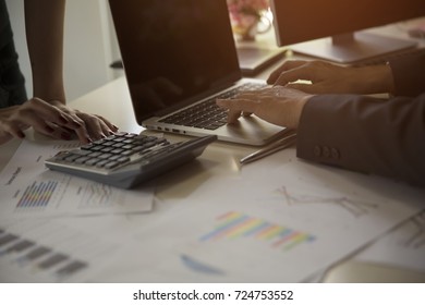 Businessman Typing On Laptop Keyboard, Business Chart Lay On Table And Someone Using A Calculator.