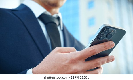 Businessman is typing text messages on mobile phone sitting in the park. Close up Male hands with smartphone, outdoors.  Human holds cell phone close up. Man holds mobile phone. Connection concept. - Powered by Shutterstock