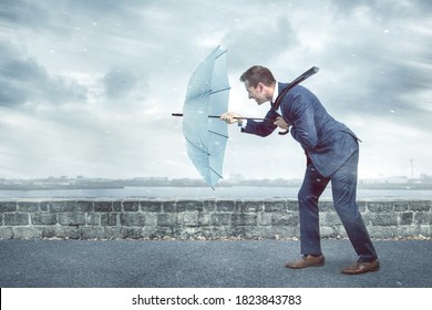 Empresario con paraguas se enfrenta a un fuerte viento de frente