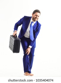 Businessman With Unhappy Painful And Stressed Face Touches His Knee, On White Background. Man In Classic Suit Feels Uncomfortable Or Injured. Illness And Pain Concept.