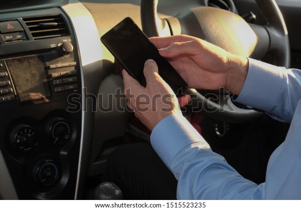 businessman use app on\
smartphone in car. caucasian man holding mobile phone checking\
direction before\
driving