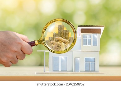 Businessman use the magnifying glass with scan and x-ray with searching for money bag and gold coin and gold bar on the home model in the public park, Loan and investment for real estate concept.