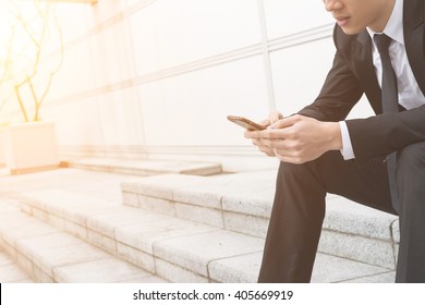 Businessman Use Of Mobile Phone And Sitting Outside