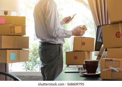 Businessman Use Smartphone Thinking With Pile Of Parcel On Work Desk