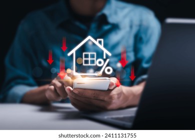 Businessman use smartphone with virtual home icon and down arrow for economical real estate and lower mortgage interest rates. Reduced prices for rental housing, Demand for home purchases decreases.