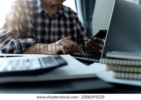 businessman used smartphone laptop and calculator on the table to run his business in small office or in home with documents including marketing information