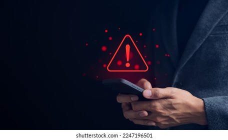 Businessman or User holding smartphone with triangle caution warning sign red for notification error and maintenance concept. warning sign exclamation, - Shutterstock ID 2247196501