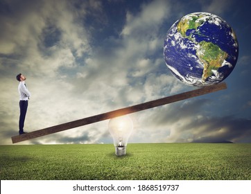 Businessman uses a lightbulb ad lever to lift the World. Earth provided by Nasa. - Shutterstock ID 1868519737