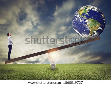 Businessman uses a lightbulb ad lever to lift the World. Earth provided by Nasa.