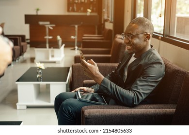 Businessman Uses Smartphone Waiting For A Flight, Traveling Entrepreneur Remote Work Online Sitting In A Boarding Lounge Of Airline Hub.