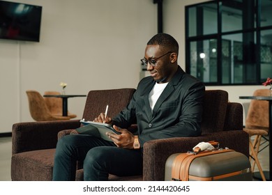 Businessman Uses Tablet Waiting For A Flight, Traveling Entrepreneur Remote Work Online Sitting In A Boarding Lounge Of Airline Hub.