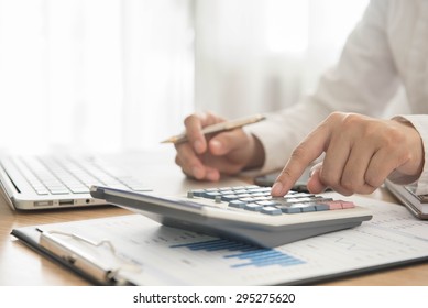 Businessman using a calculator to calculate the numbers - Shutterstock ID 295275620