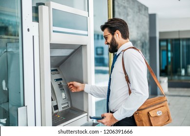 Businessman using card at an ATM 