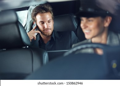 Businessman Using Cellphone In Limousine, Female Chauffeur Driving.