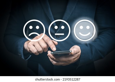 Businessman Using Cellphone For Select Smiley Face Icon For Client Evaluation And Customer Satisfaction After Use Product And Service Concept. Man Smartphone Choosing Happy Smiley Face Icon