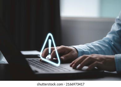 Businessman using computer laptop with triangle caution warning sign for notification error and maintenance concept. - Shutterstock ID 2166973417
