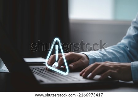 Businessman using computer laptop with triangle caution warning sign for notification error and maintenance concept.