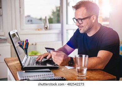 Businessman Using Credit Card And Laptop At Home Office