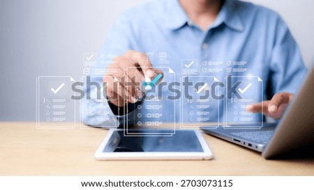 Businessman using digital checklist interface on tablet and laptop. Concept of online document verification, approval workflow, electronic forms, task management, and digitalization.