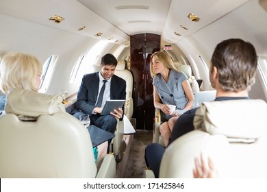 Businessman using digital tablet with colleagues in private jet - Powered by Shutterstock