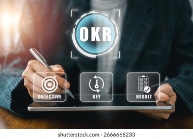 Businessman using digital tablet to explore OKR framework for strategic planning and performance enhancement.