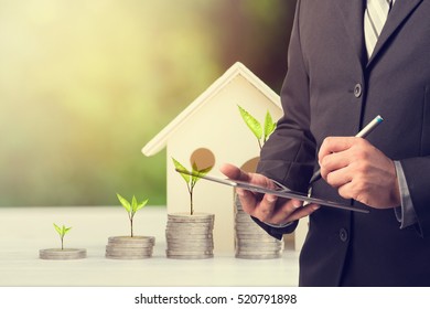 Businessman Using Digital Tablet With Stacking Coins And House Model ,Business Finance And Money Concept,Investment Concept.