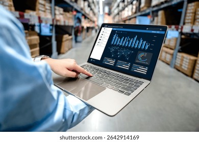 Businessman using digital warehouse inventory management dashboard system on laptop in smart warehouse, logistics technology and supply chain management concept