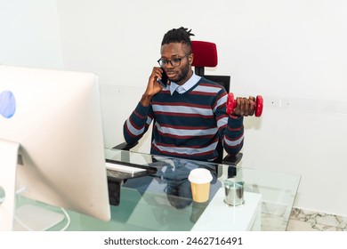 businessman using dumbbells weigth in office working - successful business man holding a heavy dumbbell - Executive exercising doing weights and working at office - Businessman in office exercising  - Powered by Shutterstock