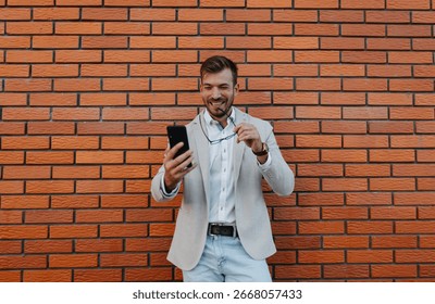 Businessman using his smartphone while standing in front of a red brick wall