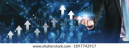Businessman using holding symbol arrow up,stock graph and chart background,concept growth business and investment,Stock market and strategy for making market plan and stock market fluctuations 