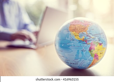 Businessman using a laptop with close up on world globe - Shutterstock ID 416963155