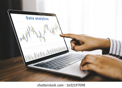 Businessman using a laptop computer with data analytics and statistics information business technology on table top. mockup with clipping path.