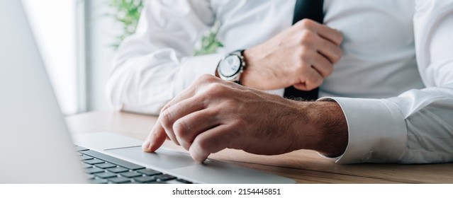 Businessman using laptop computer at office desk, hand on a trackpad or touchpad, panoramic image with selective focus